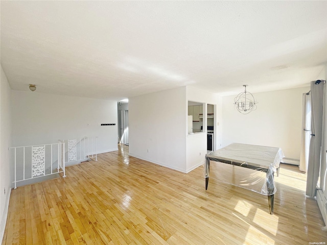 interior space featuring a chandelier, a baseboard heating unit, and light wood-type flooring