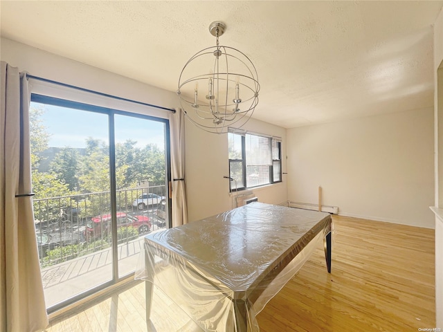 dining space featuring light hardwood / wood-style floors, a textured ceiling, and an inviting chandelier