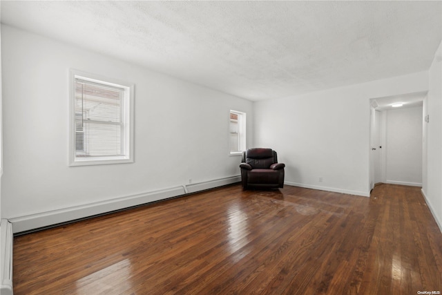 unfurnished room featuring a textured ceiling, a baseboard radiator, and dark hardwood / wood-style floors