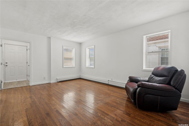 living area featuring a wealth of natural light, dark wood-type flooring, and a textured ceiling