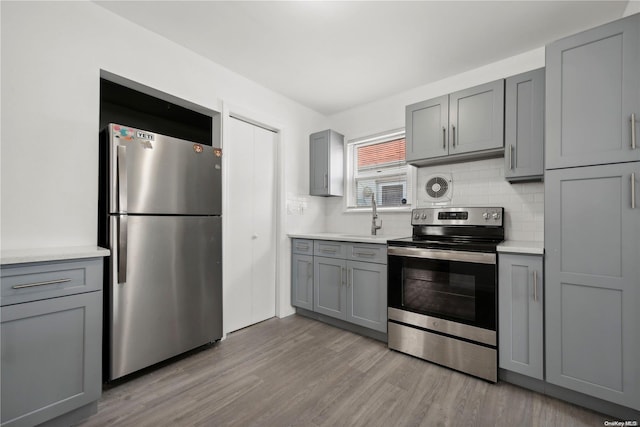 kitchen featuring gray cabinetry, light hardwood / wood-style flooring, and appliances with stainless steel finishes