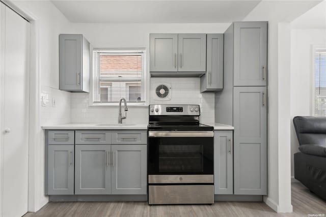 kitchen with electric range, gray cabinets, plenty of natural light, and sink