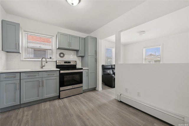 kitchen with stainless steel range with electric stovetop, backsplash, a baseboard heating unit, sink, and light hardwood / wood-style flooring