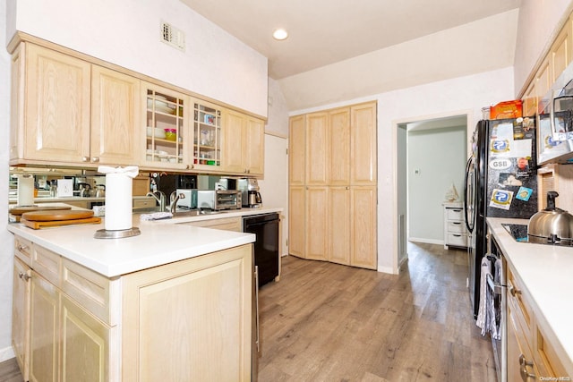 kitchen with black appliances, light brown cabinets, and light wood-type flooring