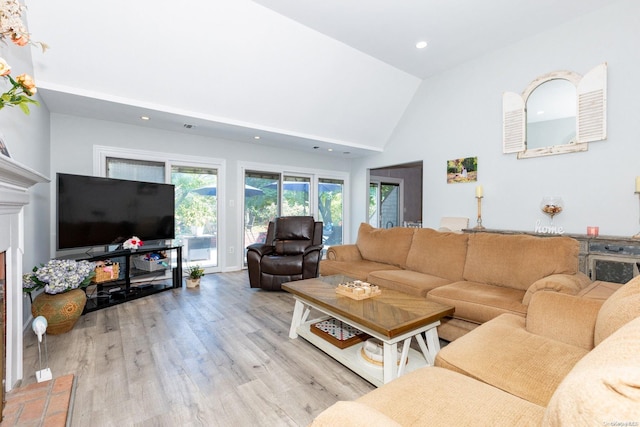 living room with high vaulted ceiling and light hardwood / wood-style flooring