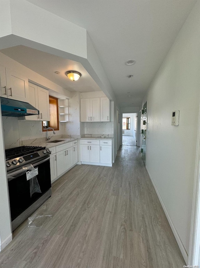 kitchen featuring sink, tasteful backsplash, stove, light hardwood / wood-style floors, and white cabinets