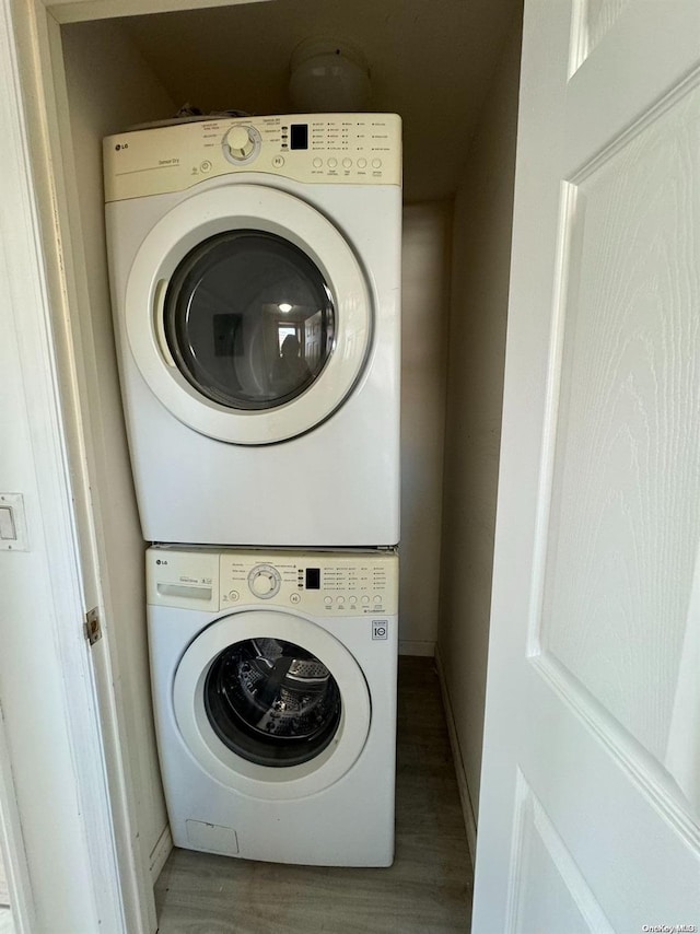 clothes washing area with hardwood / wood-style floors and stacked washer / drying machine