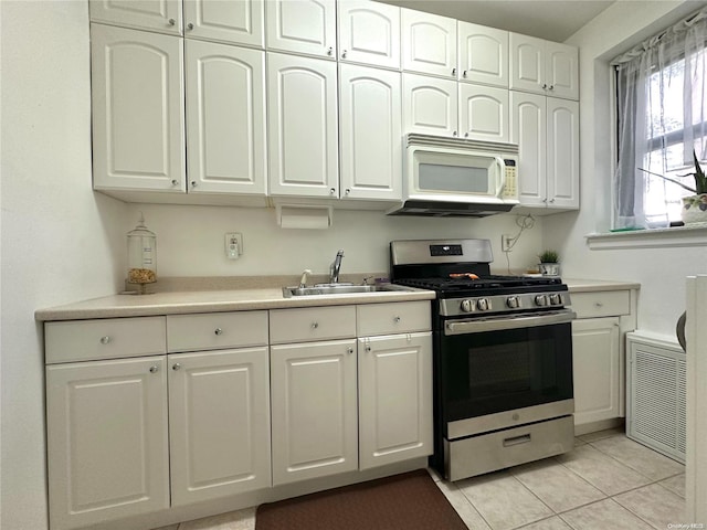 kitchen with gas stove, white cabinetry, sink, and light tile patterned floors