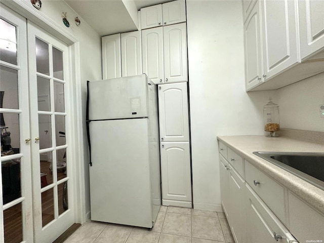 kitchen with white fridge, white cabinetry, and light tile patterned floors