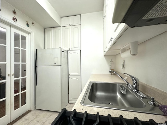 kitchen with exhaust hood, sink, light tile patterned floors, white refrigerator, and white cabinetry