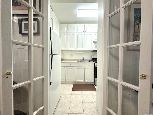 kitchen featuring white cabinets, light tile patterned floors, white appliances, and sink