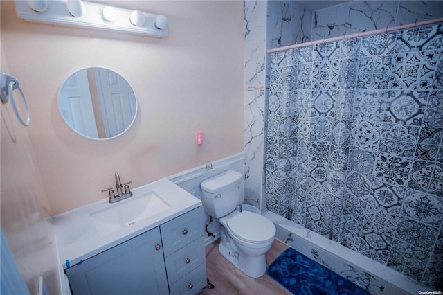 bathroom featuring tiled shower, hardwood / wood-style floors, vanity, and toilet