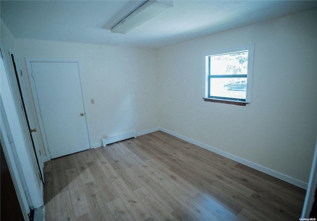 spare room with light wood-type flooring and a baseboard heating unit