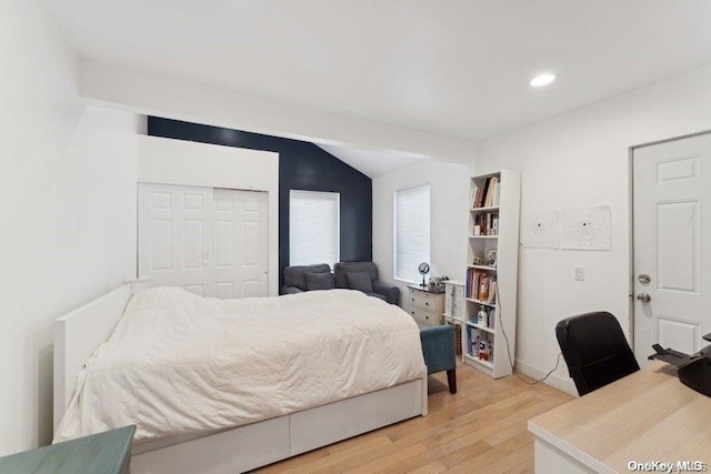 bedroom featuring hardwood / wood-style flooring, vaulted ceiling, and a closet