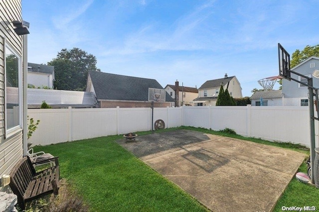 view of yard with basketball hoop and a patio