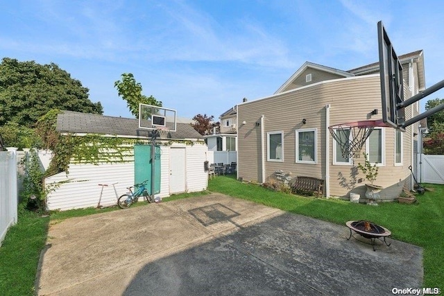 back of property with a patio area, a shed, and an outdoor fire pit