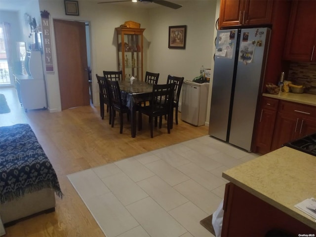 kitchen featuring ceiling fan, stainless steel fridge, backsplash, and light hardwood / wood-style flooring