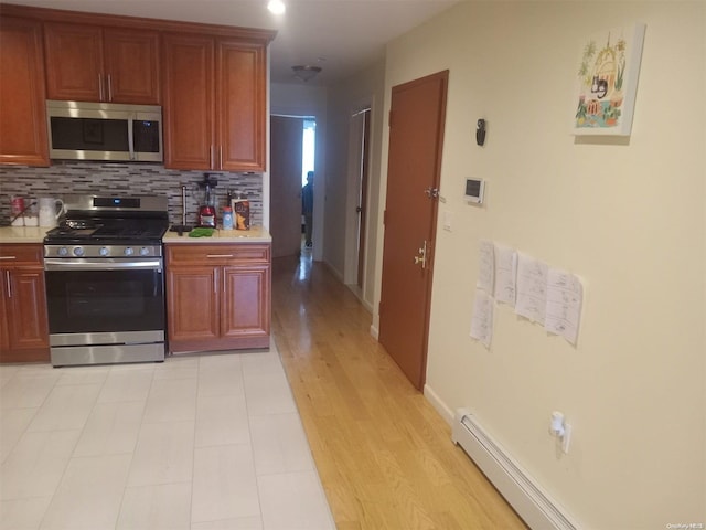 kitchen with backsplash, light hardwood / wood-style floors, stainless steel appliances, and a baseboard heating unit