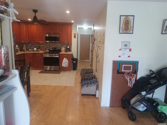 kitchen with light wood-type flooring, backsplash, stainless steel appliances, ceiling fan, and sink