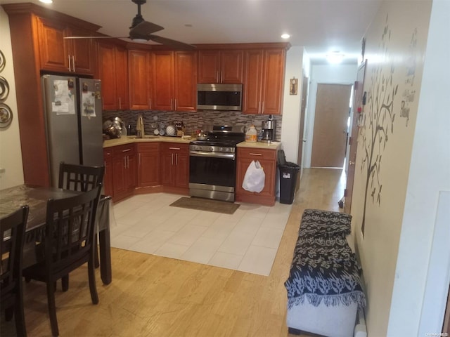 kitchen with appliances with stainless steel finishes, tasteful backsplash, ceiling fan, sink, and light hardwood / wood-style floors