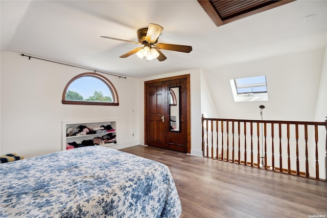 bedroom featuring ceiling fan, light hardwood / wood-style floors, lofted ceiling with skylight, and a closet