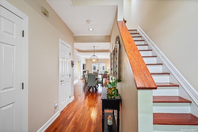 stairs featuring hardwood / wood-style floors and a chandelier