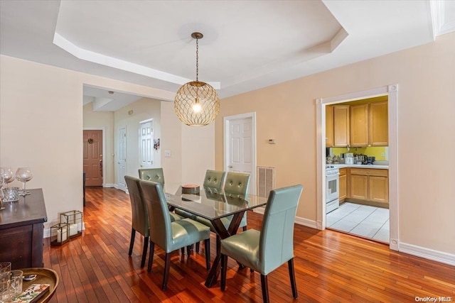 dining area featuring a raised ceiling and light hardwood / wood-style floors