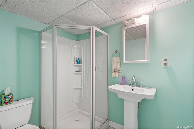 bathroom with a drop ceiling, toilet, and a shower with shower door