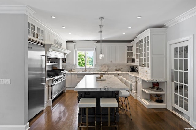 kitchen with a center island, premium range hood, crown molding, decorative light fixtures, and high quality appliances