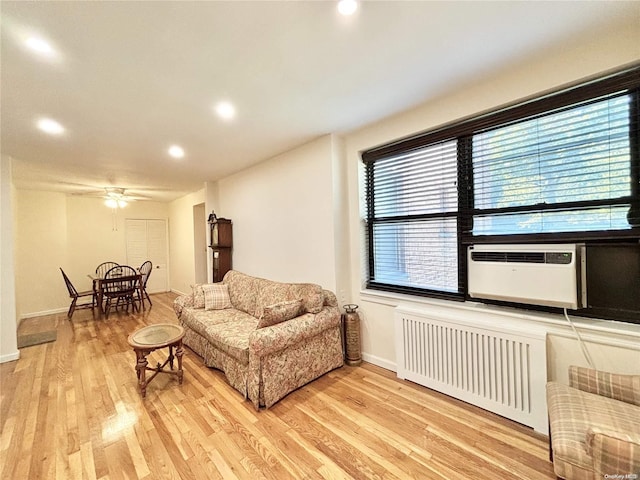 living room featuring radiator, ceiling fan, cooling unit, and light hardwood / wood-style floors