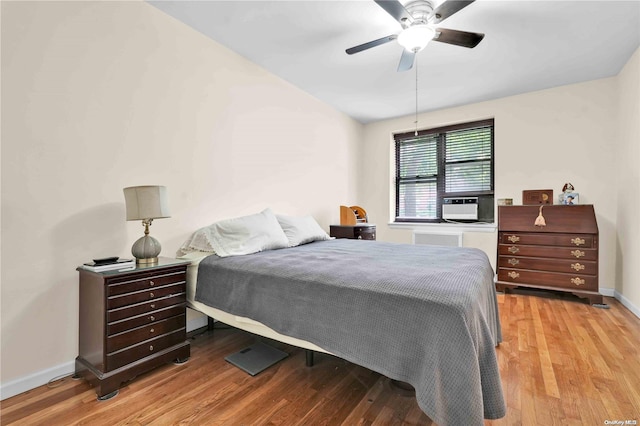 bedroom with light wood-type flooring, ceiling fan, and cooling unit