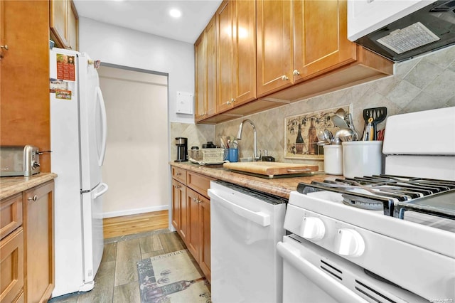 kitchen featuring decorative backsplash, white appliances, and light wood-type flooring