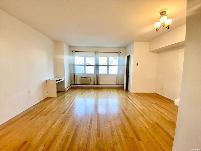 spare room featuring baseboard heating, light hardwood / wood-style flooring, and an inviting chandelier