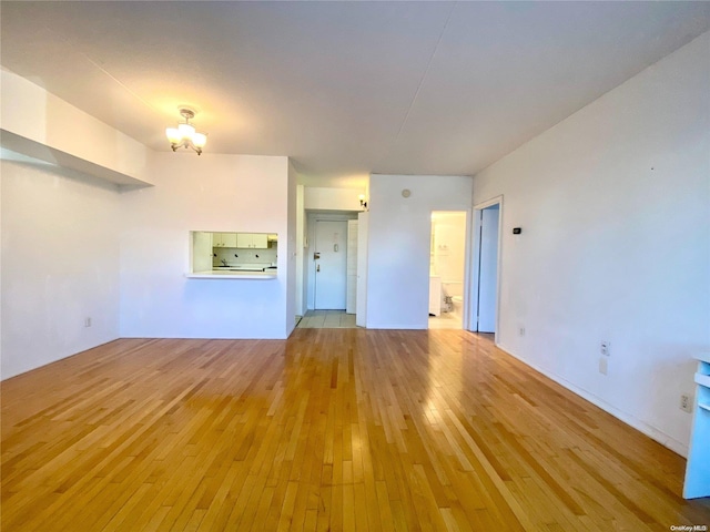 unfurnished living room with light hardwood / wood-style flooring and a notable chandelier