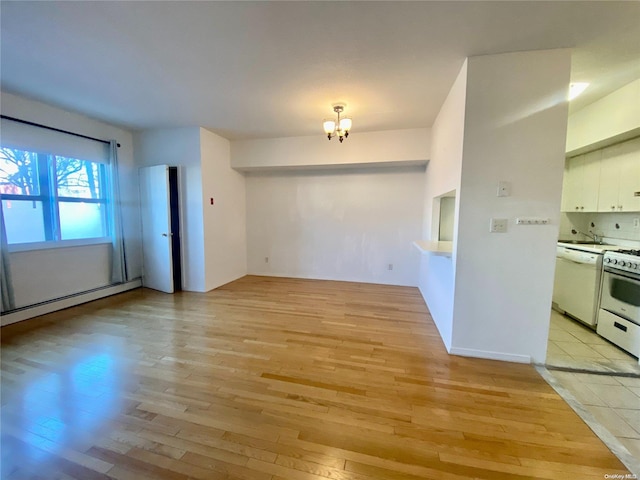 empty room featuring baseboard heating, light hardwood / wood-style floors, and an inviting chandelier