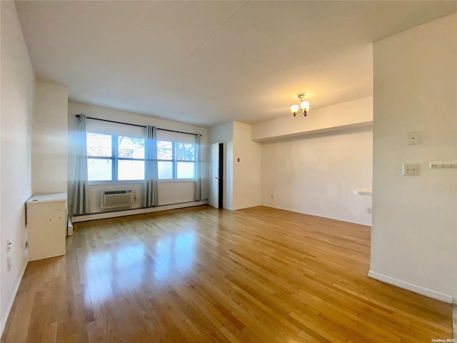 empty room with an AC wall unit, light hardwood / wood-style floors, and a baseboard heating unit