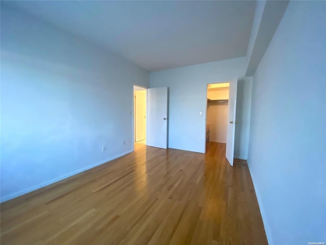 unfurnished bedroom featuring a spacious closet, a closet, and hardwood / wood-style flooring