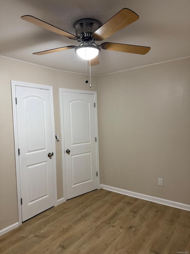 empty room featuring baseboards, ceiling fan, crown molding, and light wood-style floors