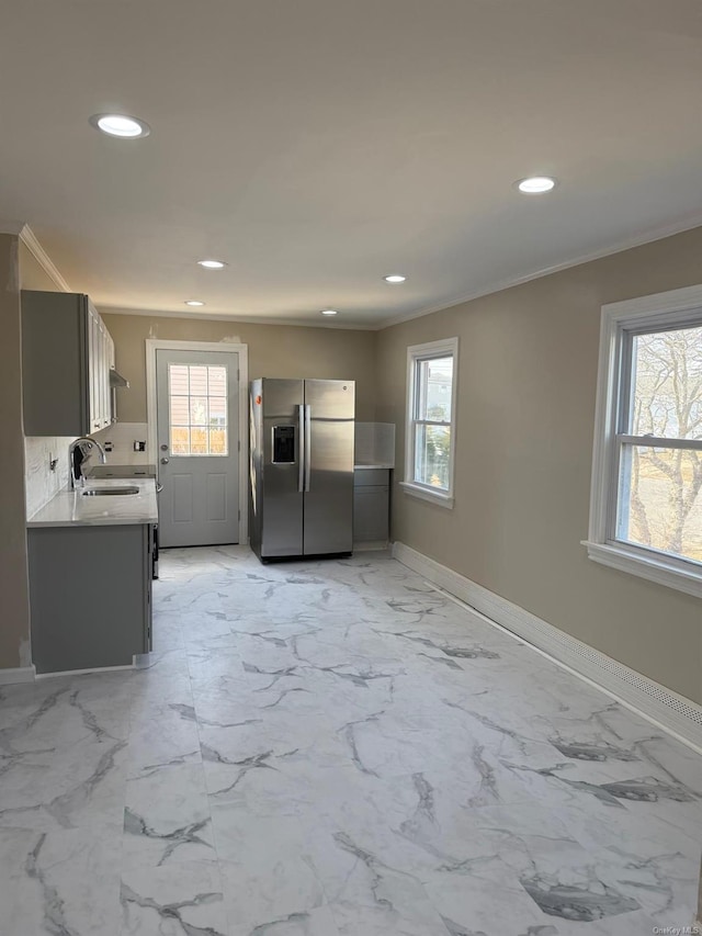 kitchen featuring recessed lighting, baseboards, light countertops, ornamental molding, and stainless steel fridge