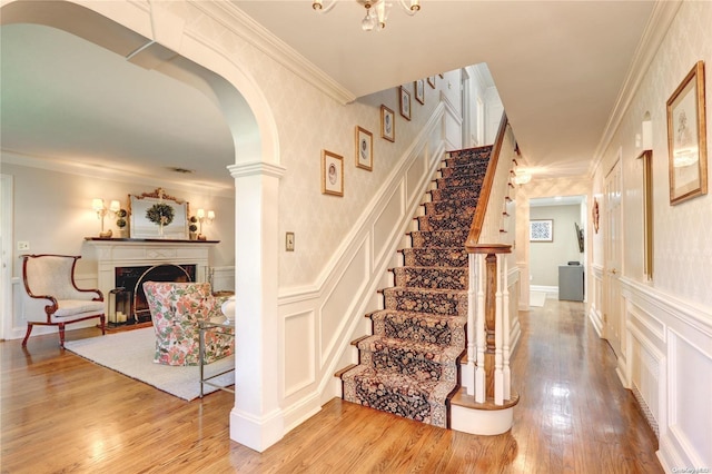 stairway with wood-type flooring and ornamental molding