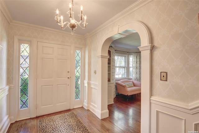 entryway with hardwood / wood-style floors, ornamental molding, and a chandelier