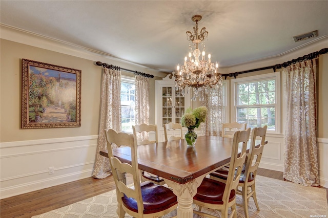 dining space with ornamental molding, light hardwood / wood-style floors, and a notable chandelier