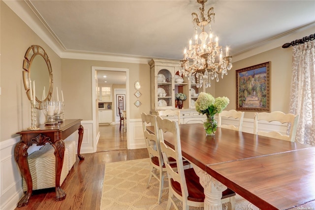 dining space with a chandelier, hardwood / wood-style flooring, and ornamental molding