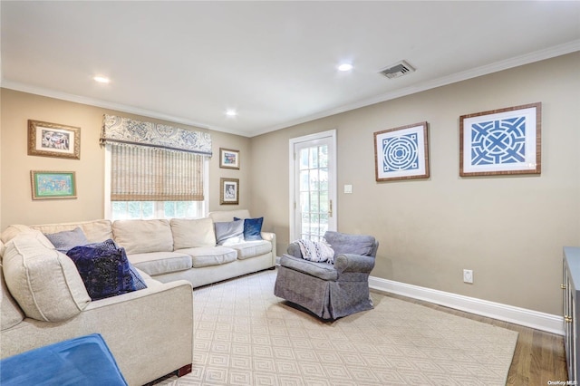 living room with a healthy amount of sunlight, wood-type flooring, and ornamental molding