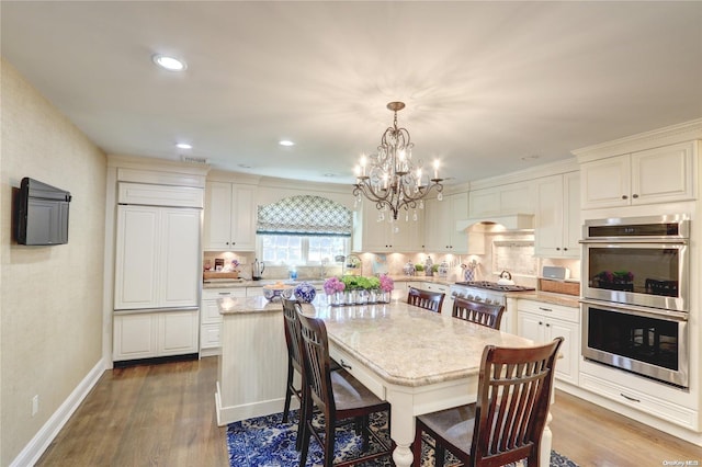 kitchen featuring a center island, hanging light fixtures, hardwood / wood-style floors, a chandelier, and appliances with stainless steel finishes