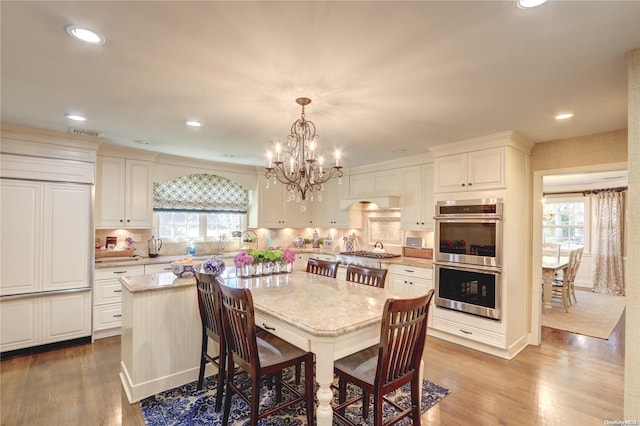 dining space with a notable chandelier, plenty of natural light, and light wood-type flooring