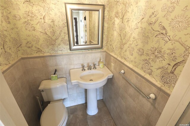 122 Roxen Rd, Rockville Centre, NY 11570 - half bathroom featuring a wainscoted wall, toilet, wallpapered walls, tile patterned floors, and tile walls