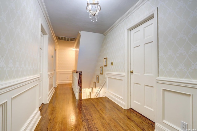 corridor with an inviting chandelier, ornamental molding, and hardwood / wood-style flooring