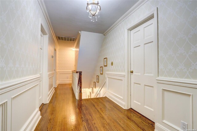 122 Roxen Rd, Rockville Centre, NY 11570 - hallway with an upstairs landing, wood finished floors, wallpapered walls, a decorative wall, and crown molding