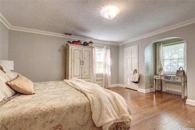 bedroom with dark hardwood / wood-style flooring, crown molding, radiator, and multiple windows